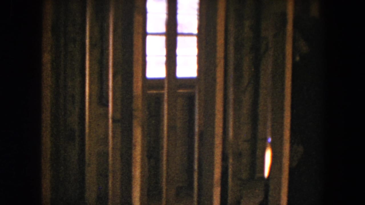 Dim unfinished room with wall studs, doorway framing, and bright windows.