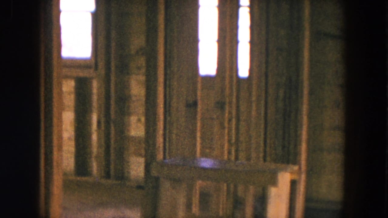 Unfinished house interior with exposed studs and bright narrow windows.