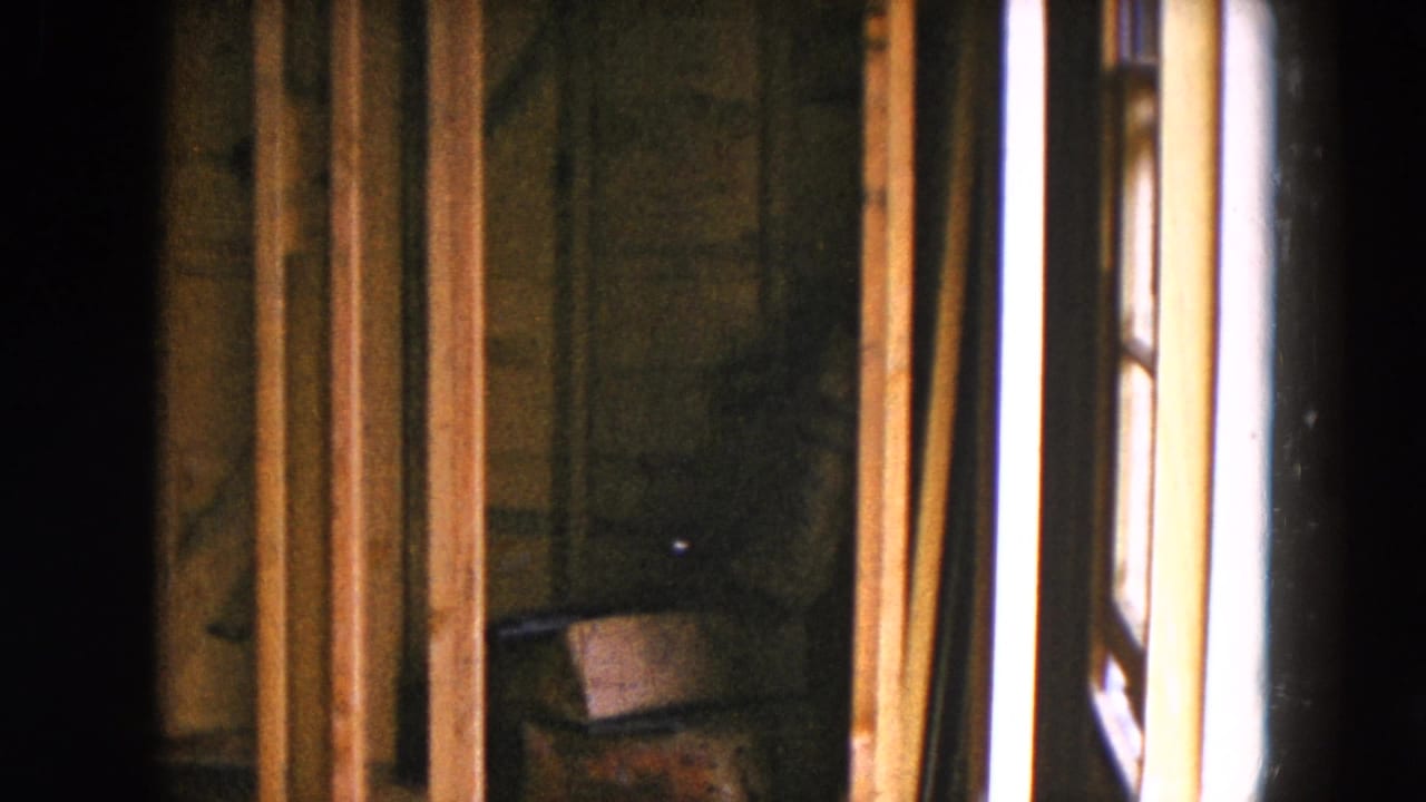 1954 8mm frame from Hicksville showing wooden framing or a doorway edge before the exterior house view.