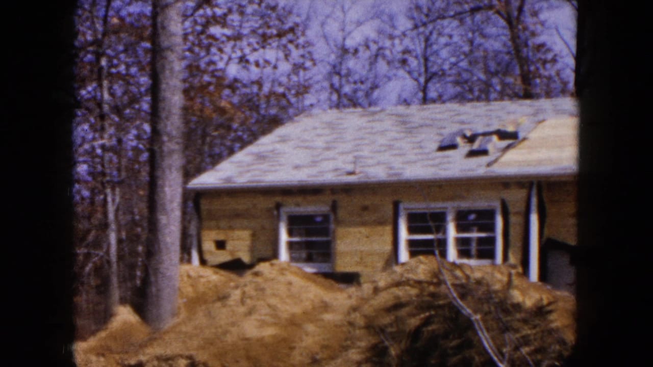 House under construction behind dirt piles with bare trees in the background.