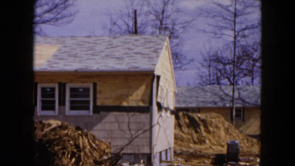 The final frame shows the end of the Hicksville house under construction, with exposed wall surfaces, nearby excavation, bare trees, and a neighboring building.
