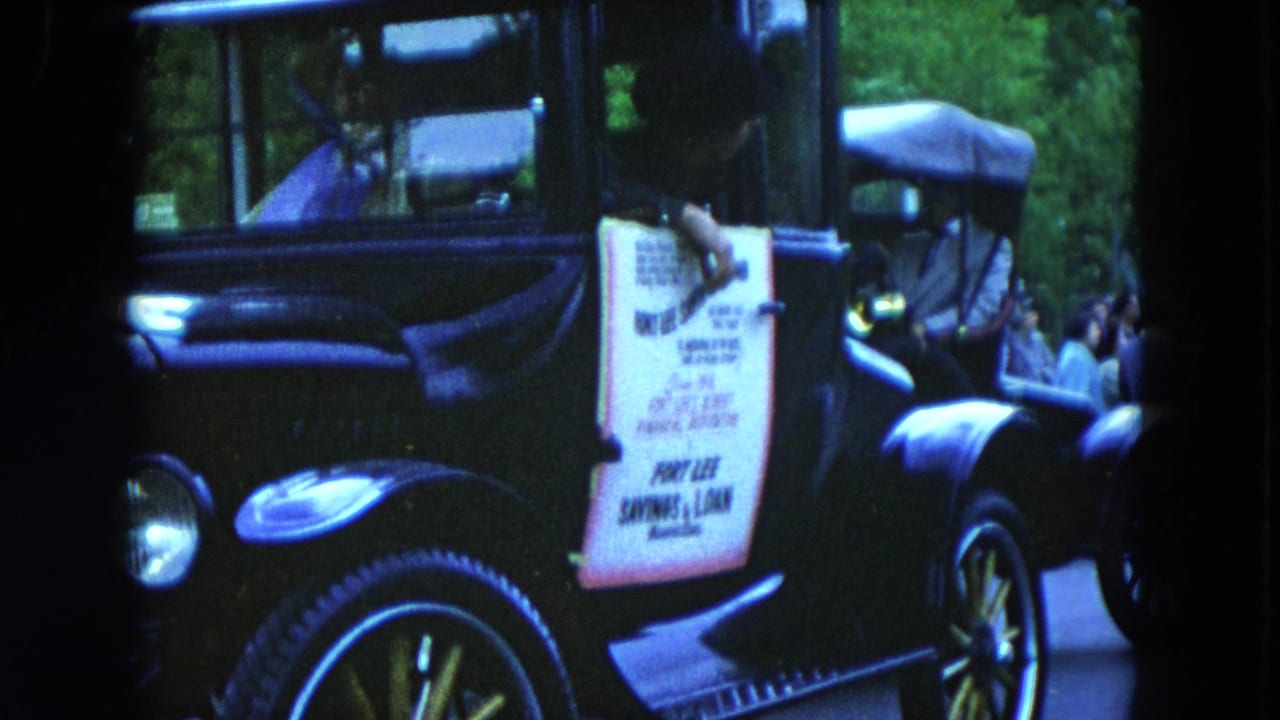 Black vintage car with a white Fort Lee Savings & Loan sign on its side.