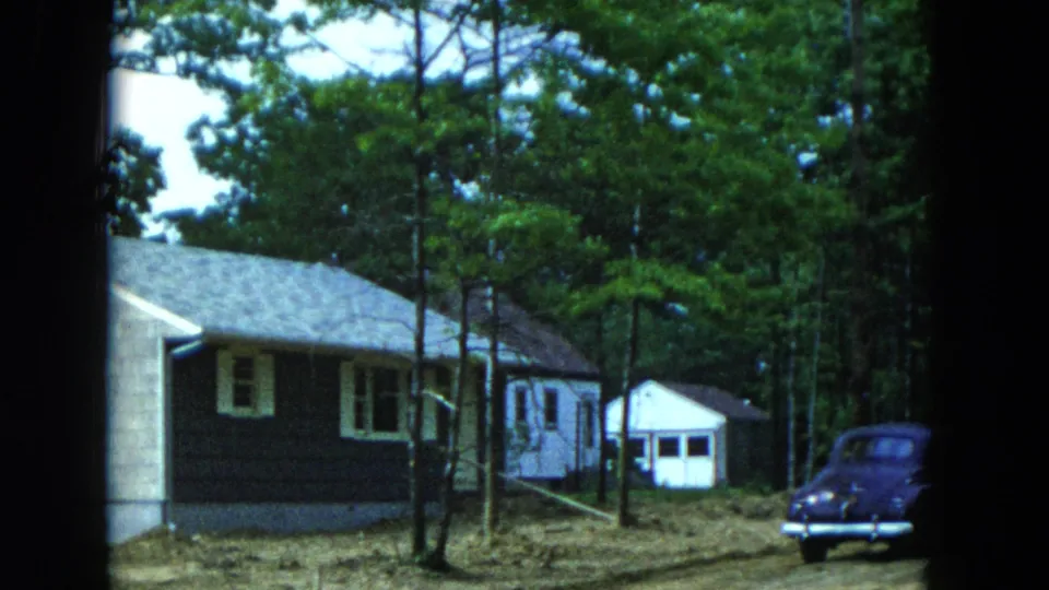 Final 1954 Hicksville frame with the suburban house, shed, trees, and a blue-purple 1950s sedan parked at right.