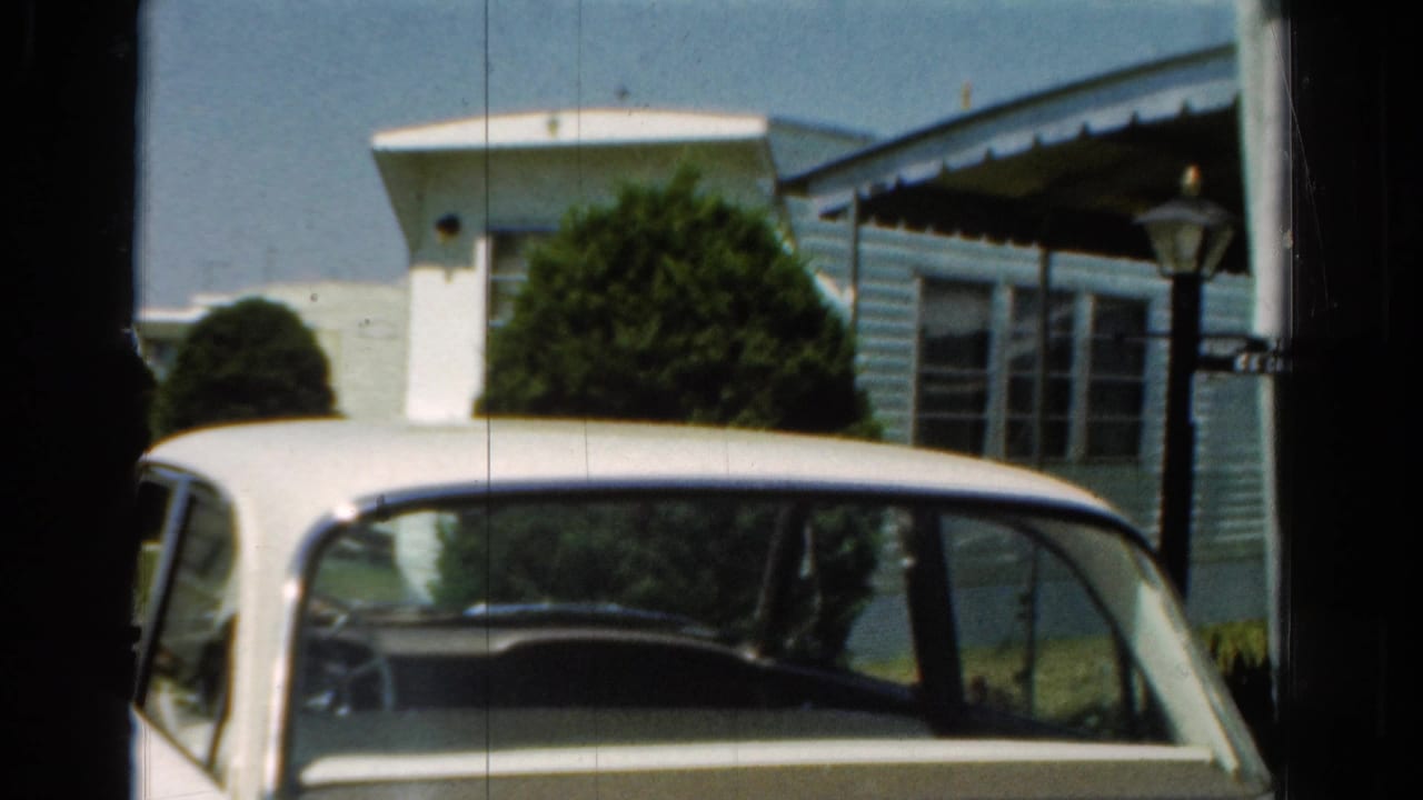 Final frame of the static 1954 California shot, showing the parked white sedan near a mobile home in bright sun.