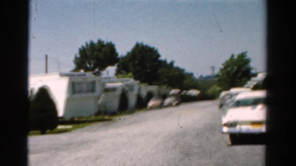 A wider 1954 California view shows trailer homes, trees, and vintage cars along a bright mobile home park road.