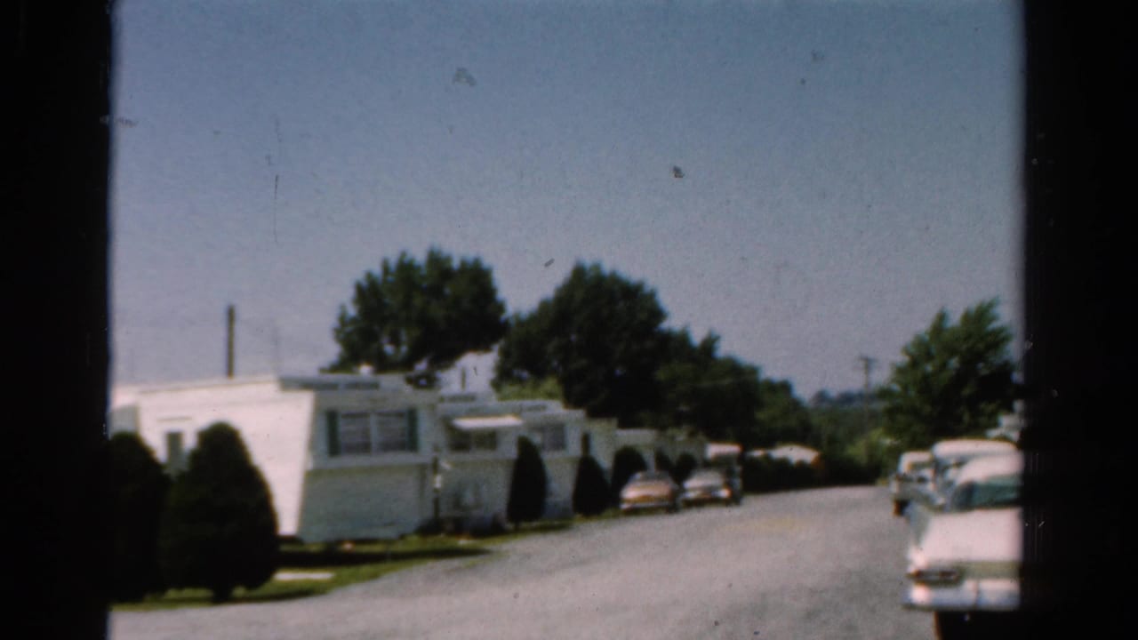 White mobile homes and parked cars along a sunny residential street.