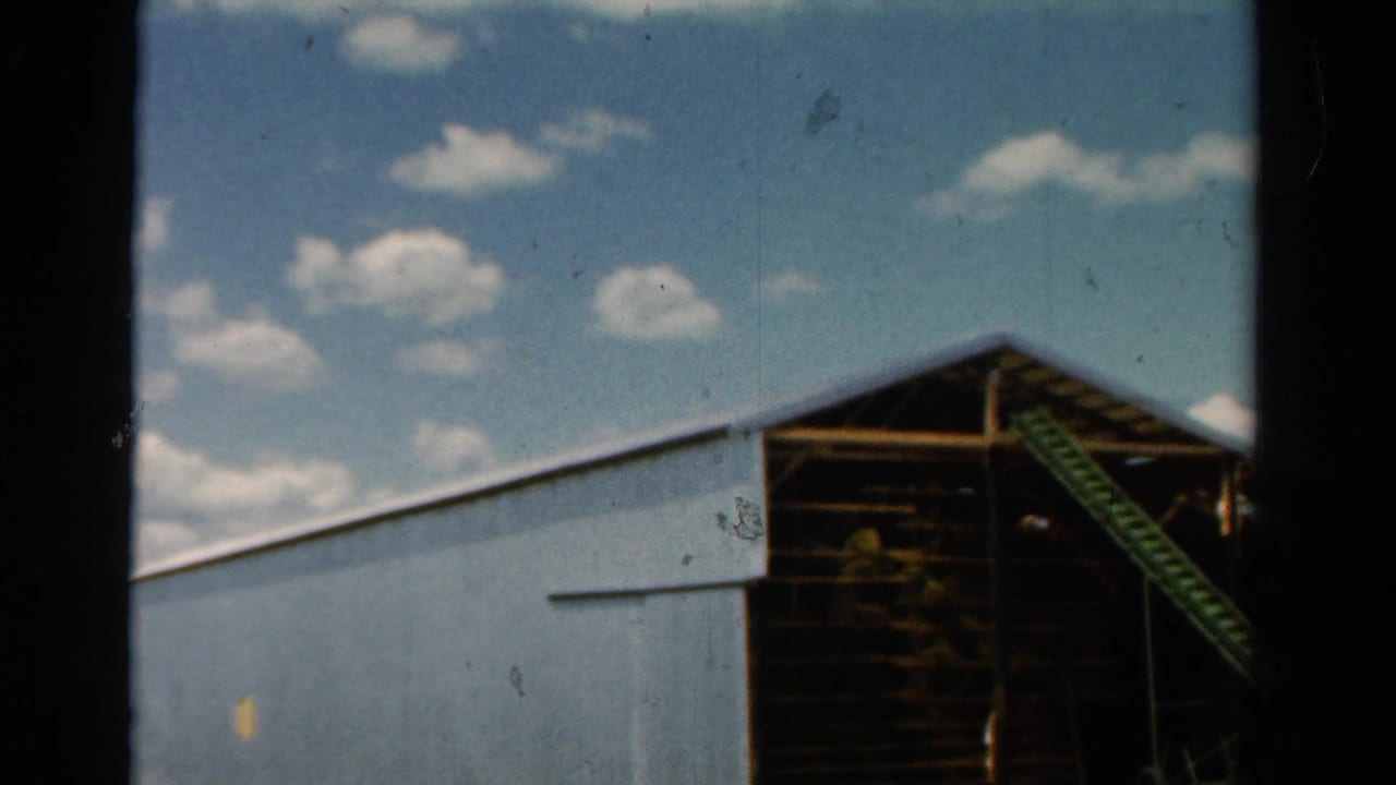 Corrugated rural barn with open framing under a partly cloudy sky.