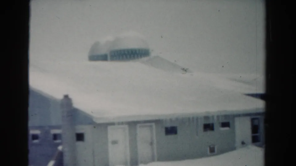 1954 Toledo winter frame with the snow-covered building facade, icicles along the eaves, small windows, and visible 8mm frame edge.