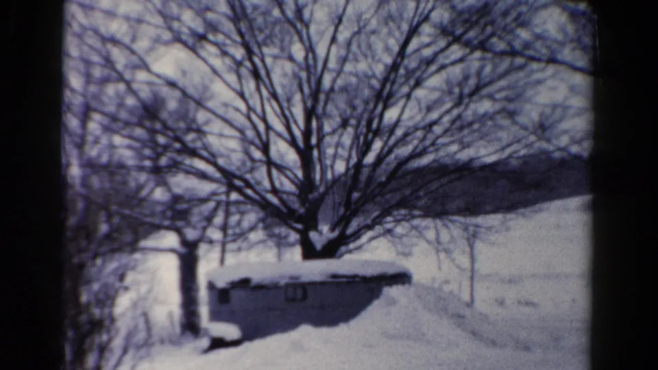 1954 Toledo, Ohio winter frame with a low shed in snow, leafless trees, and a pale open landscape behind it.