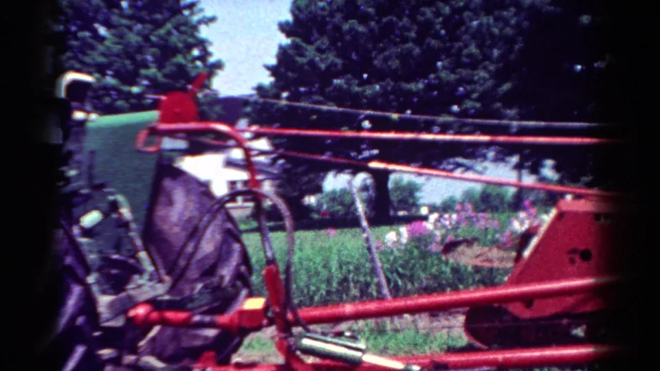 Final frame of the 1954 Toledo-area tractor clip, emphasizing the red implement and green tractor beside a grassy rural backdrop.