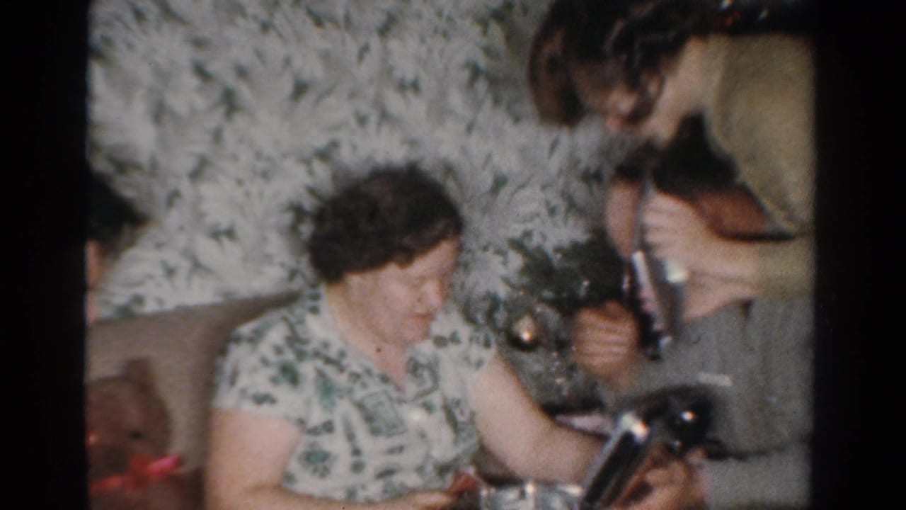 Older woman seated near a Christmas tree while a younger woman helps with an object.
