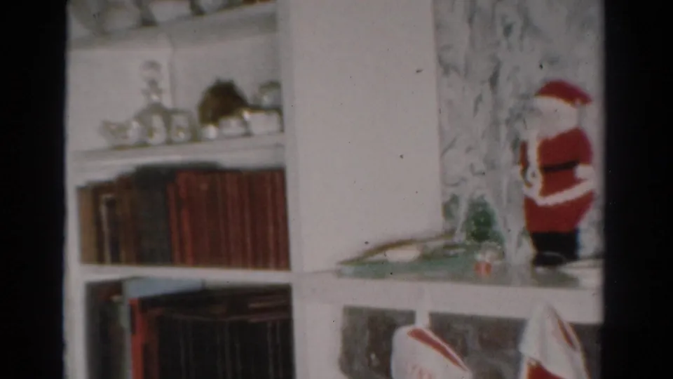 1954 Toledo home interior with a small Santa figurine, bookshelves, floral wallpaper, and holiday decor.