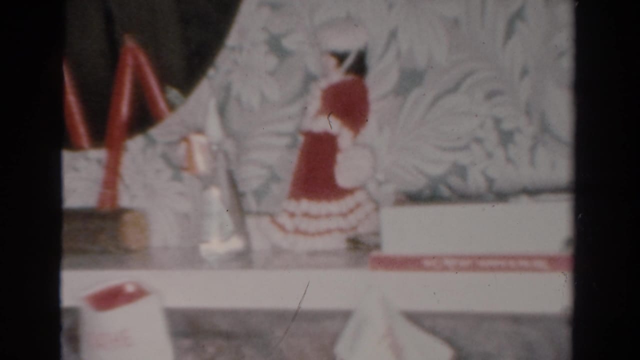 1954 Toledo home interior detail of Christmas mantel decorations, including red candles and a red-and-white holiday figurine.