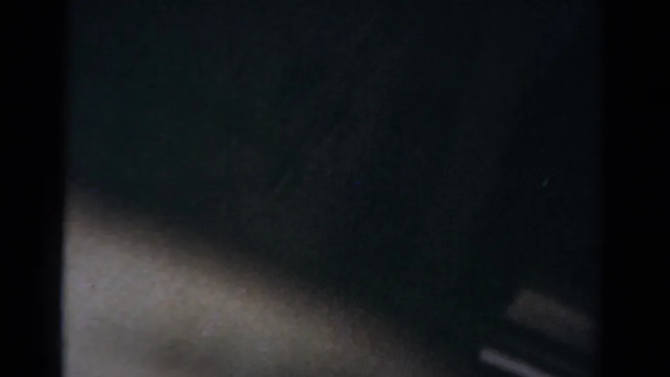 Dim 1954 Toledo home-movie frame with heavy blur, dark foreground shapes, and a pale lower edge suggesting snow or reflected light.
