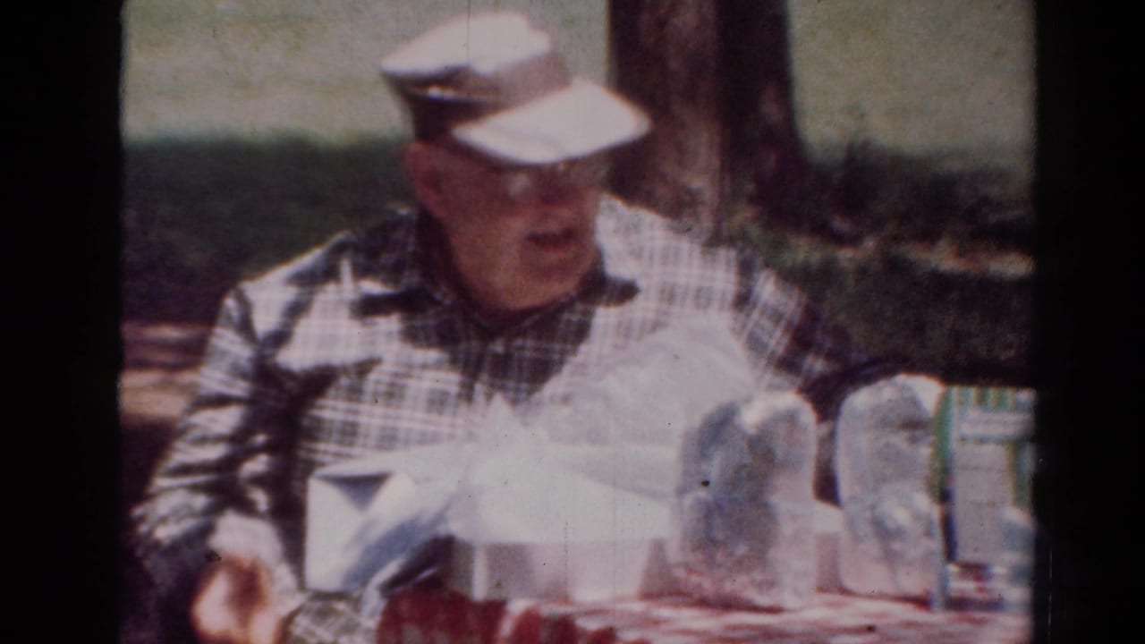 Man in visor turns beside packaged items on a table outdoors.