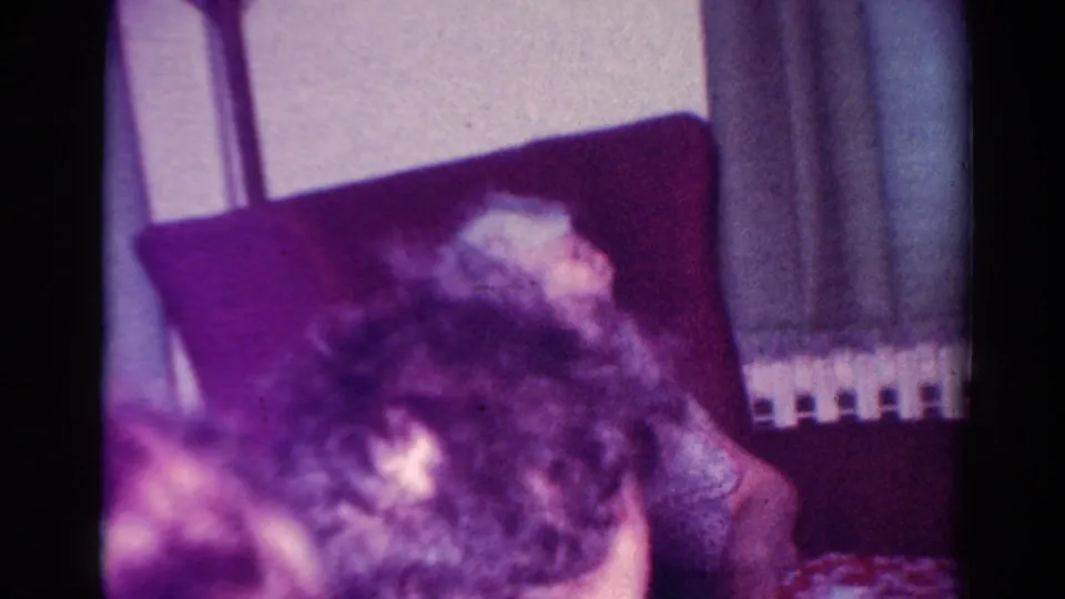 1954 Toledo Christmas-season home-movie frame with family members seated close together in a private living room.