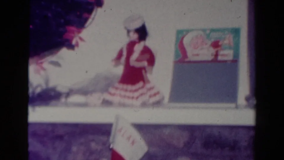 1954 Toledo home-movie frame showing a Christmas mantel display with a red-and-white figure and a stocking hanging near the hearth.
