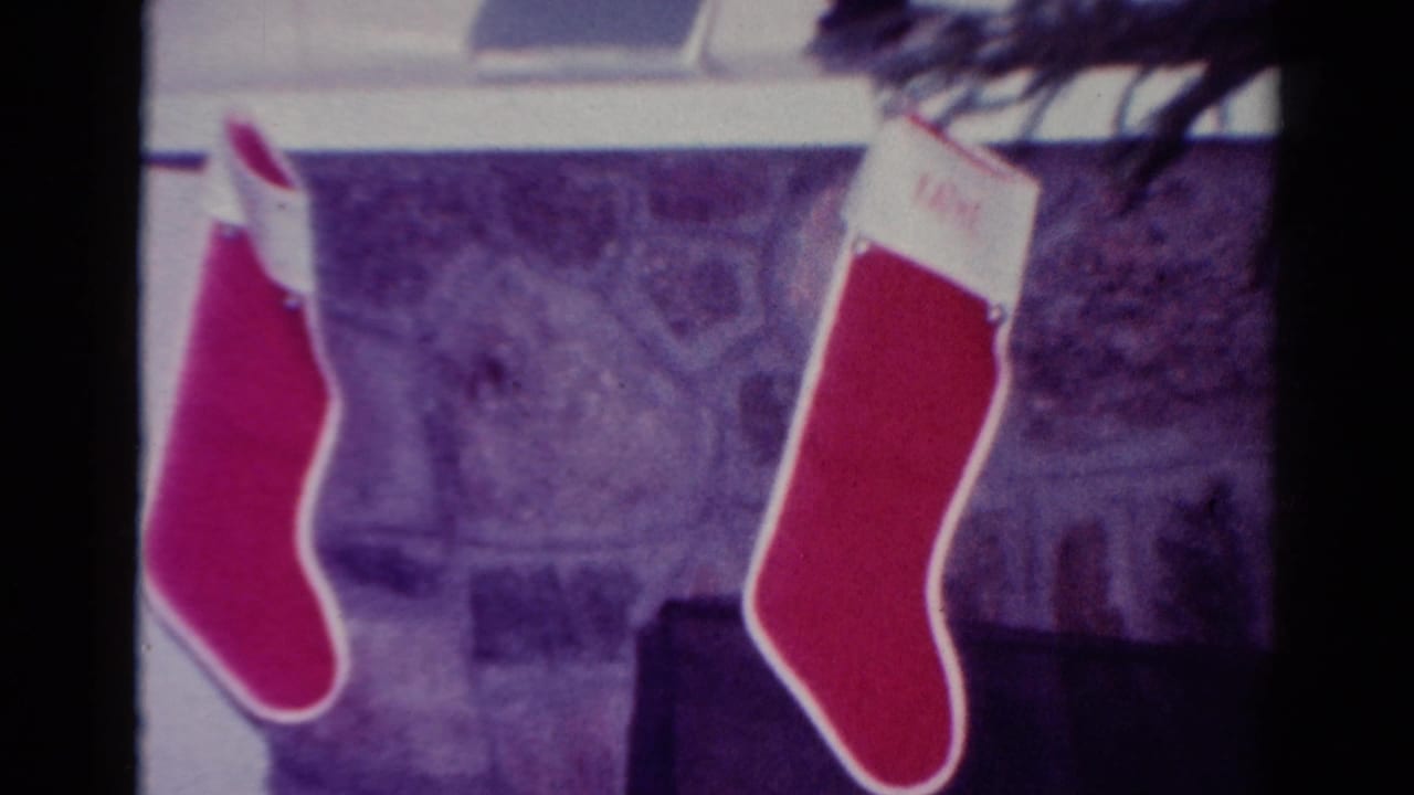 Two red stockings hang near a stone fireplace and window area.