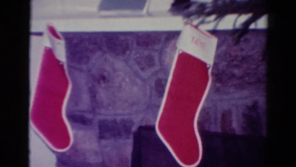 1954 Toledo home-movie frame with two red stockings hanging near a stone fireplace and interior window trim.