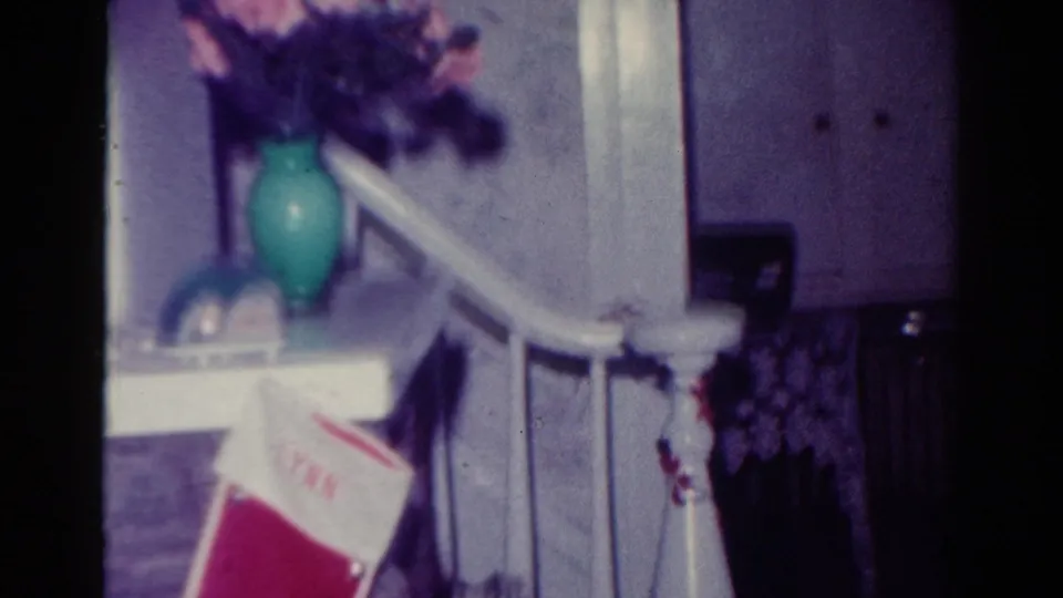 A red stocking with the name LYNN hangs near a white stair rail, with a green vase and pink flowers above in the Toledo holiday interior.