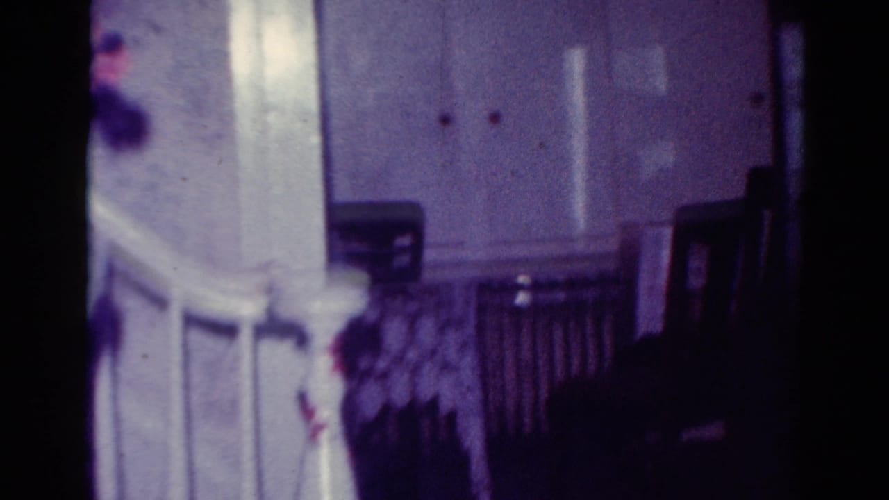 Soft 8mm view of a white staircase railing and dim living room furnishings.