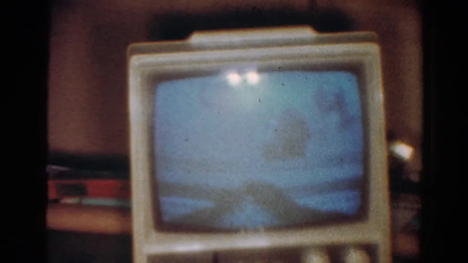 1954 Toledo frame of a bulky CRT television, its blue screen flickering while the cabinet and controls remain out of focus.