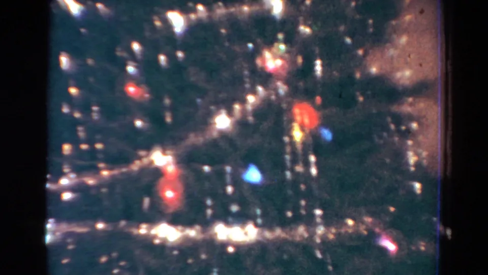 1954 Toledo 8mm frame showing a Christmas tree close-up with tinsel garland, colored bulbs, and soft home-movie blur.