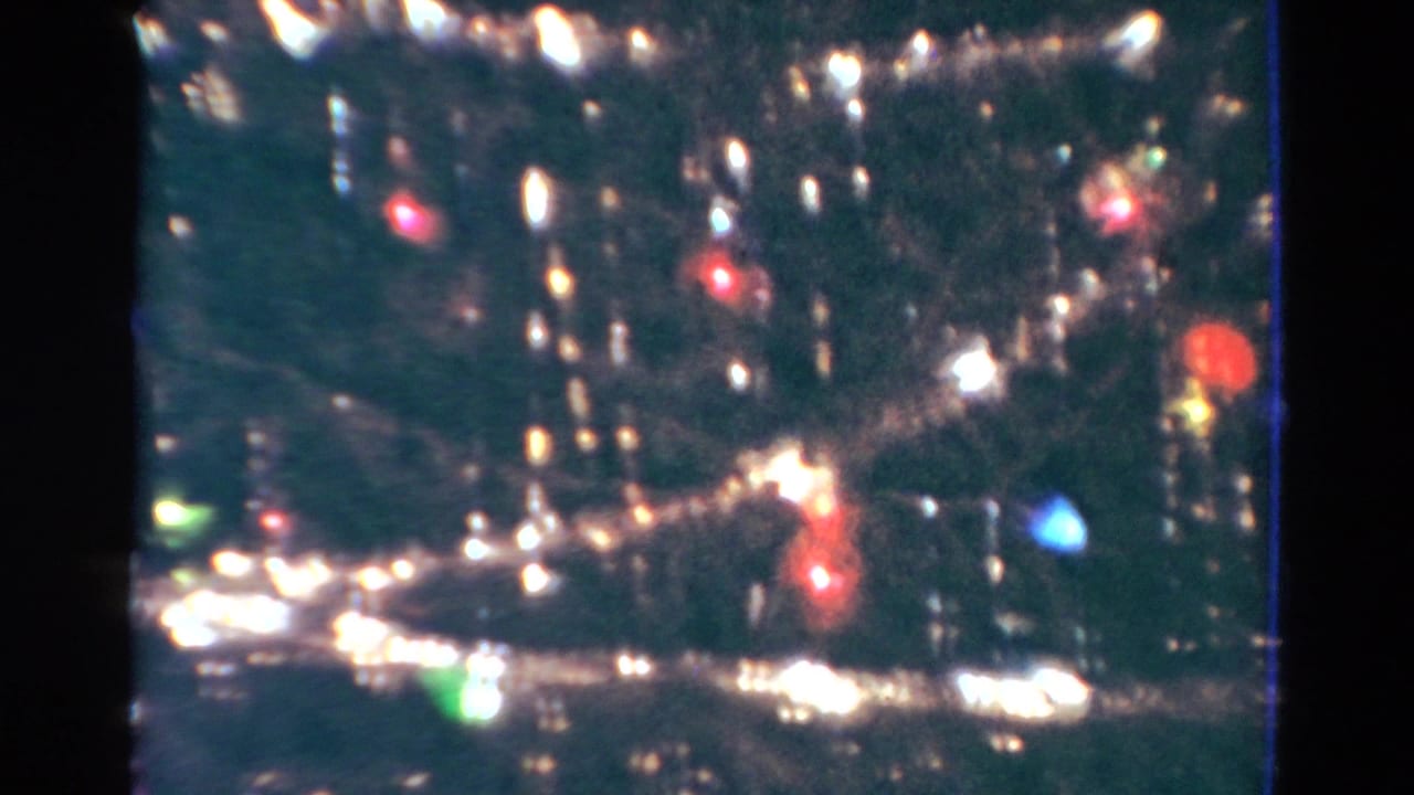 Close view of a Christmas tree with tinsel, lights, and ornaments in soft focus.