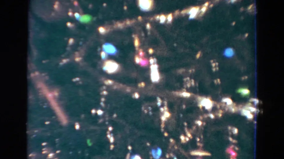 1954 Toledo home-movie close-up of a Christmas tree dense with tinsel, colored bulbs, and shiny ornaments.