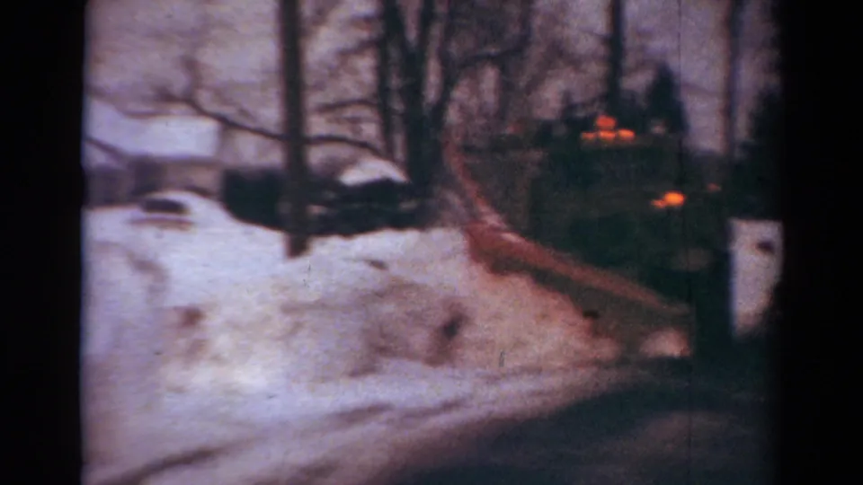 Soft 8mm frame from Toledo in 1954 showing a work truck clearing snow on a quiet residential street.