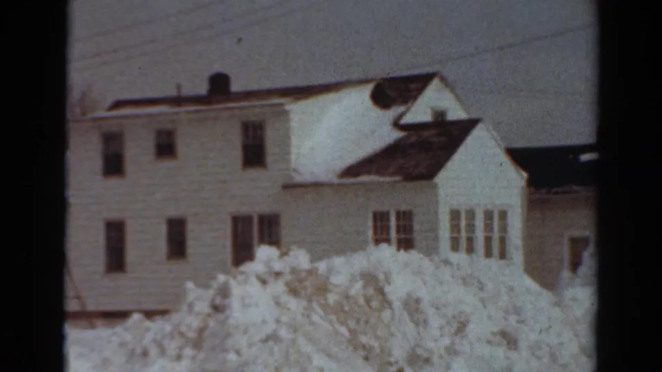 1954 Toledo residential houses with snow on roofs and large snowbanks in a quiet winter street view.