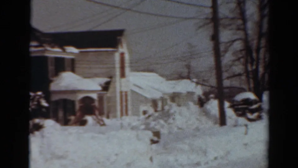 1954 Toledo winter frame with a two-story house, nearby homes, heavy snowbanks, bare trees, and utility lines.