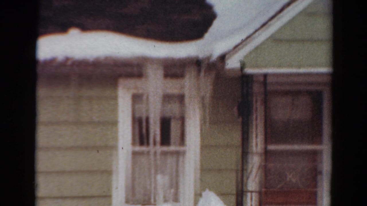 House exterior with snowy eaves, white windows, and part of a porch or entry area.