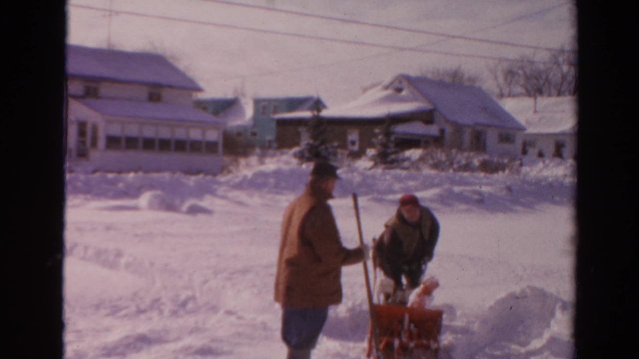 A man with a shovel watches as another works at the snow blower in a snowy 1954 Toledo neighborhood.