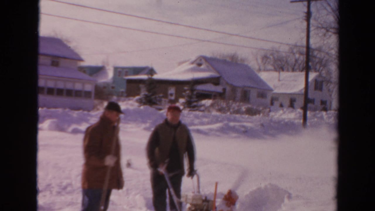 Two men in winter clothing approach the camera during residential snow clearing in supported 1954 Toledo home-movie footage.