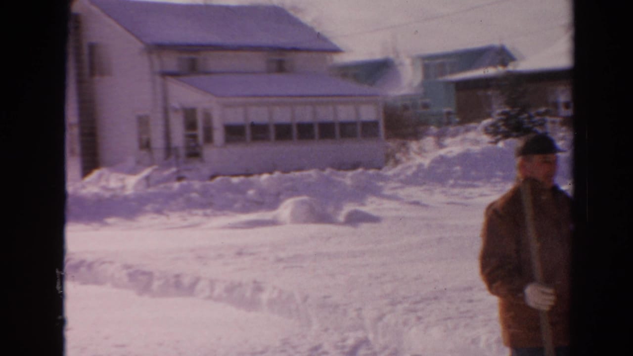 Snow-covered houses and a man partly visible at the right edge.