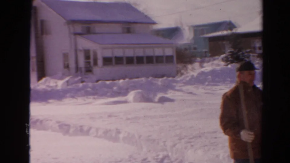A snowy Toledo residential block appears with an adult man partly framed at right, near houses and high snowbanks.