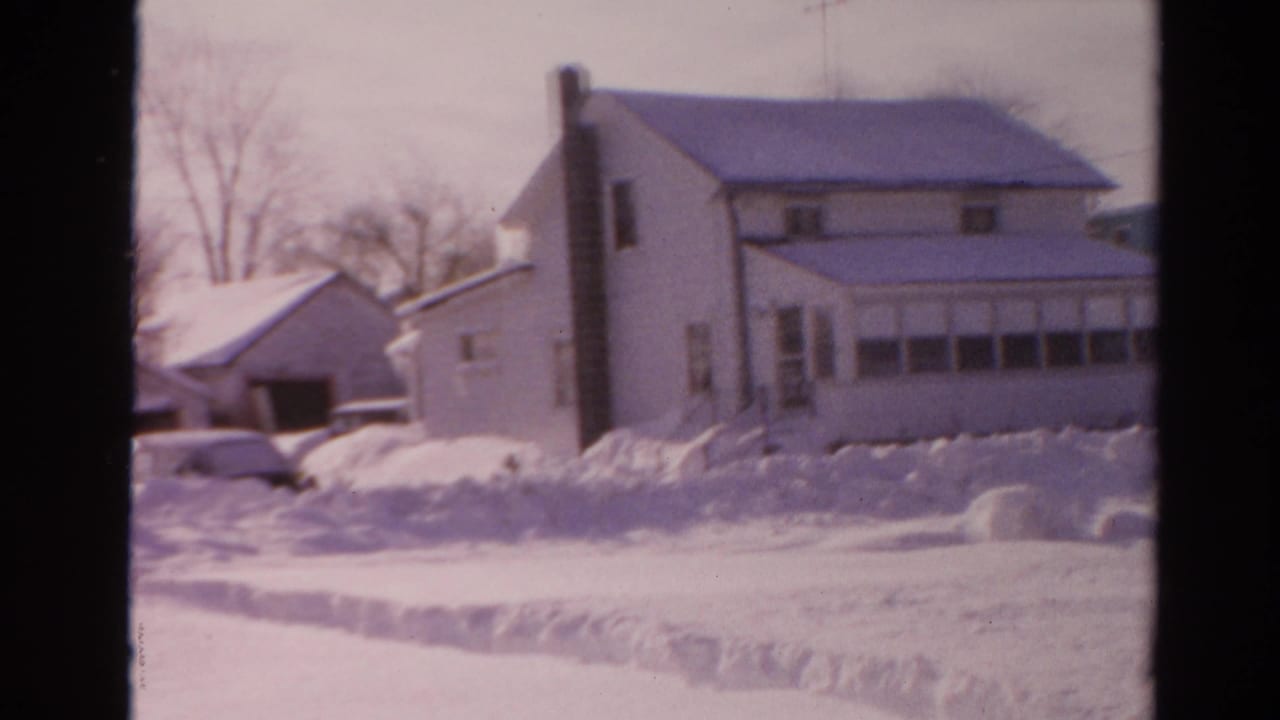 A 1954 Toledo winter view shows snow-covered suburban houses, a garage, bare trees, and piled snow along the street.