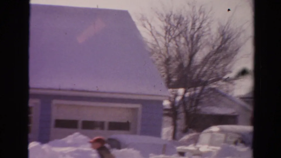 1954 Toledo winter frame with deep snow around a garage, bare tree, and partially visible older car at the edge of the shot.
