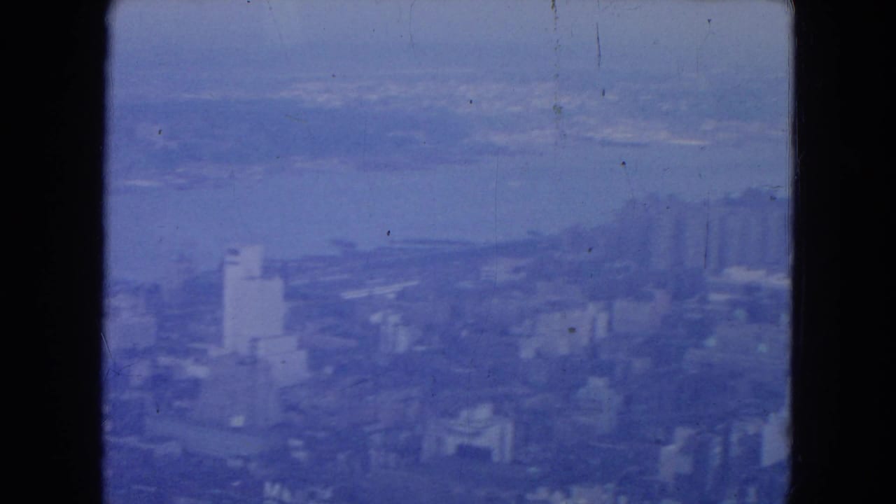 Hazy blue-tinted city skyline with distant water and dark 8mm frame borders.