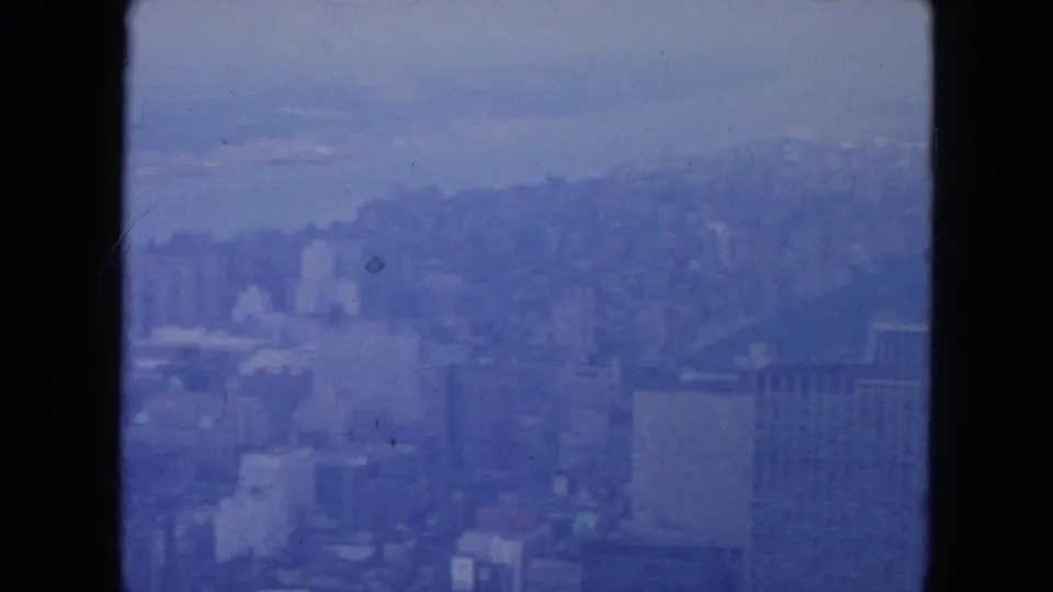 New York City in 1954 appears through faded blue 8mm stock, with skyline forms, waterfront haze, and visible film scratches.