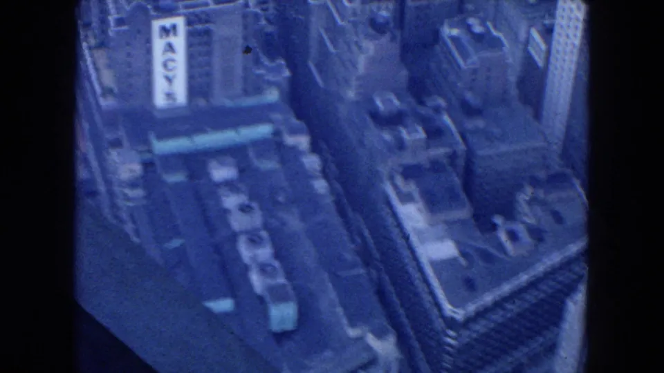 1954 New York City aerial frame with Macy's sign near the upper center, surrounded by rooftops and commercial towers.