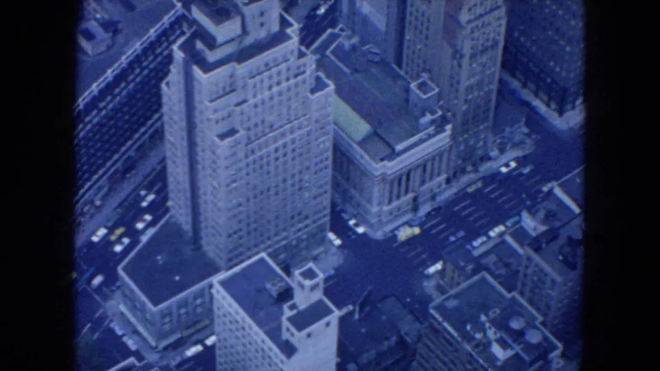 1954 New York City aerial view looking down on tall buildings, a columned structure, rooftops, and traffic in the streets.