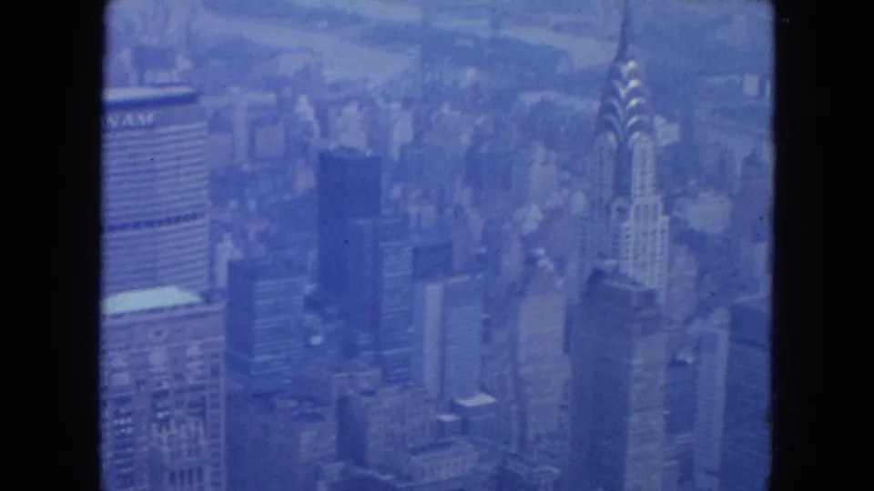 New York City aerial frame with mid-century towers, a Pan Am marking at left, and the Chrysler Building rising at right.