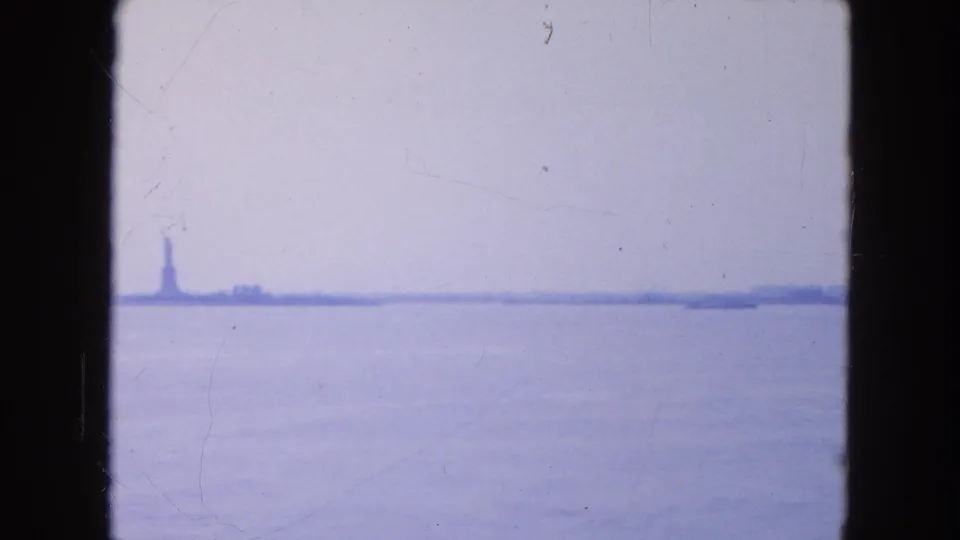 Distant Statue of Liberty across New York Harbor in a blue-tinted 1954 8mm boat view.