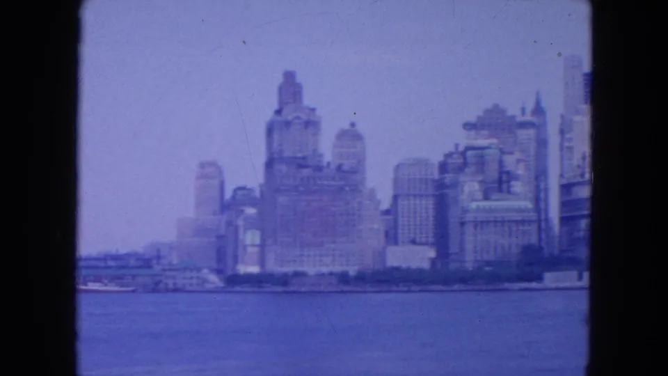 A closer portion of the 1954 New York City skyline appears across the water, with prominent waterfront architecture and soft focus.