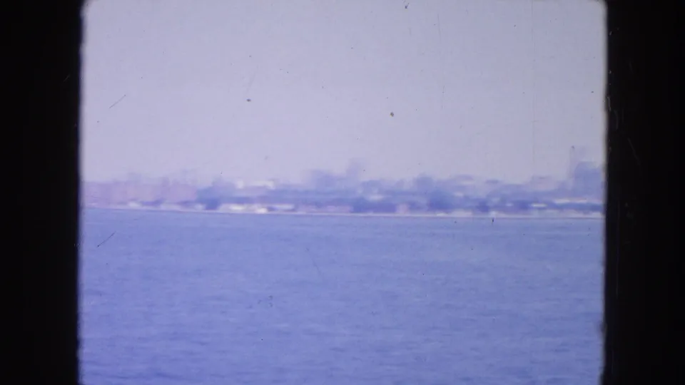 Soft 8mm view across New York Harbor toward a hazy shoreline, with open water filling most of the frame.