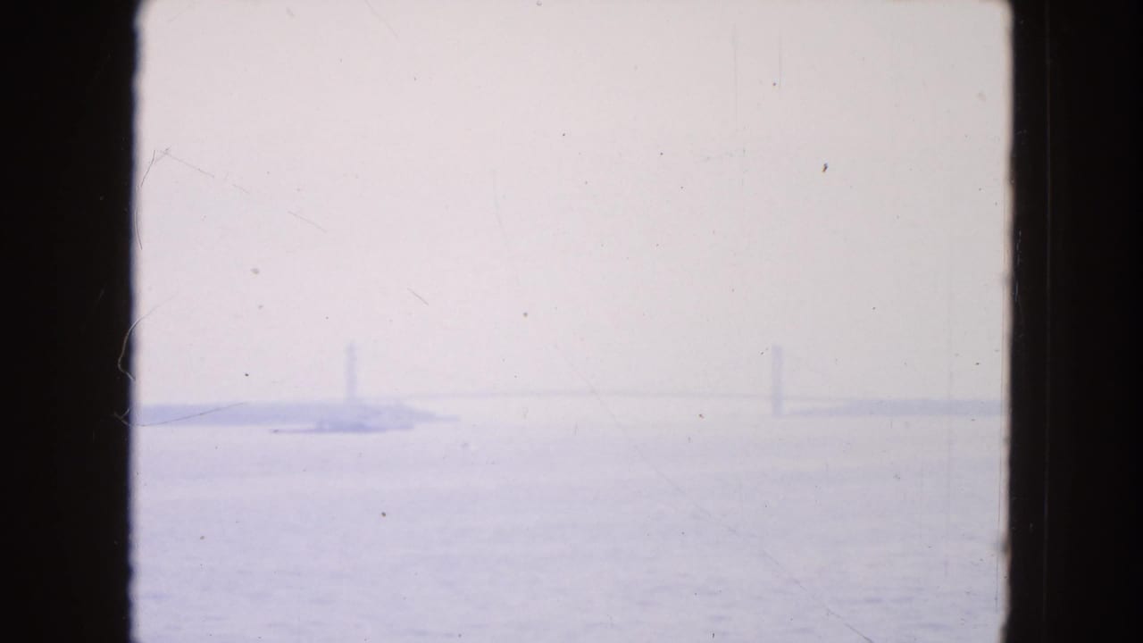 Hazy harbor water with faint bridge-like structures in the distance.