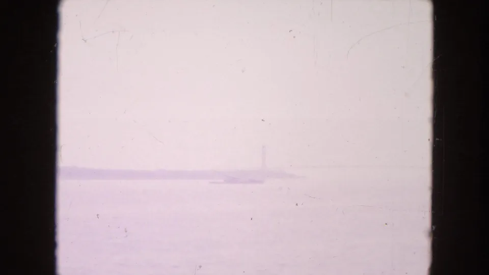 Washed 1954 New York City 8mm frame showing a barely visible waterfront horizon with faint vertical structures and heavy film wear.