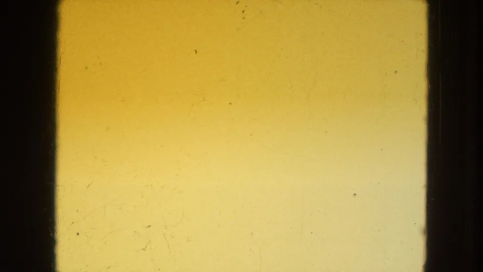Yellow 8mm leader-like or exposure frame from the 1954 New York City clip, with dark borders and visible film surface marks.